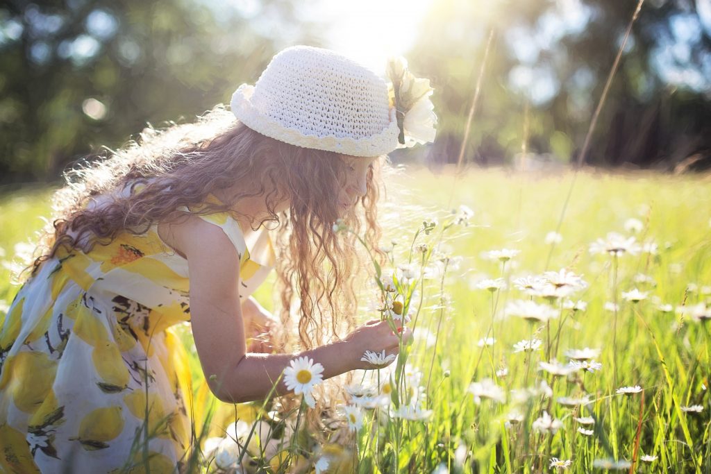 Petite fille qui sent les fleurs au printemps.