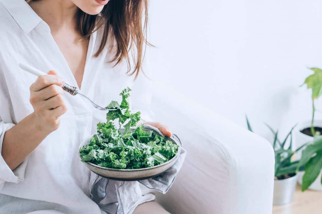 Femme mangeant une salade de chou frisé en bonne santé.