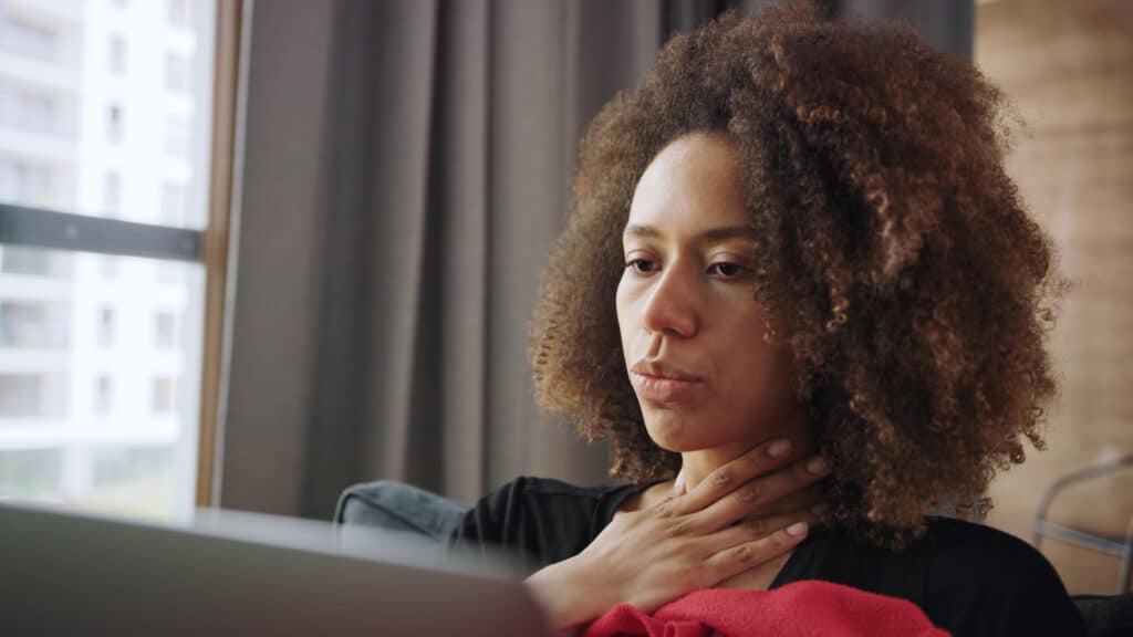 Femme avec un mal de gorge se reposant à la maison.