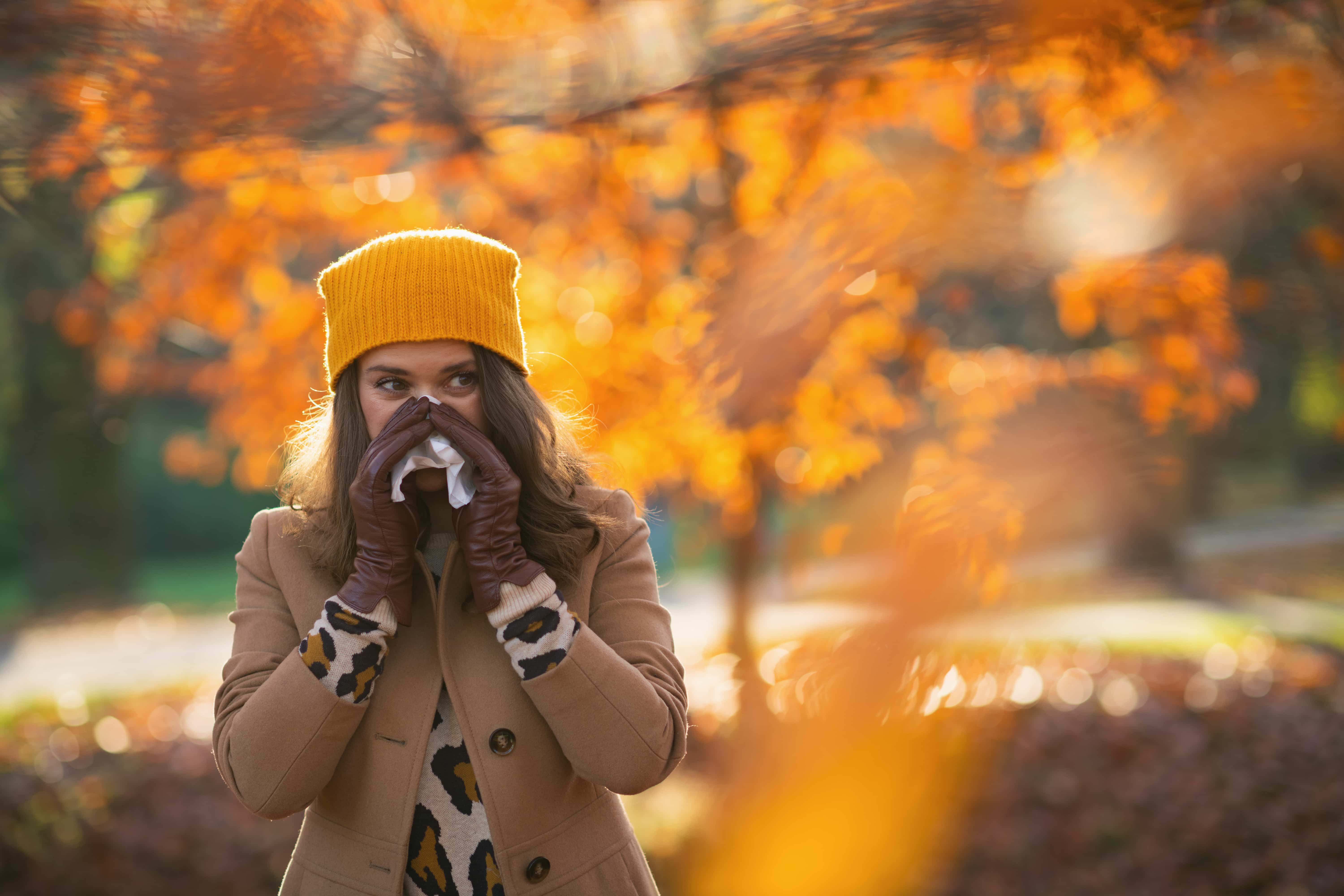 femmes se mouchant et éternuant dans un parc pendant l'automne.