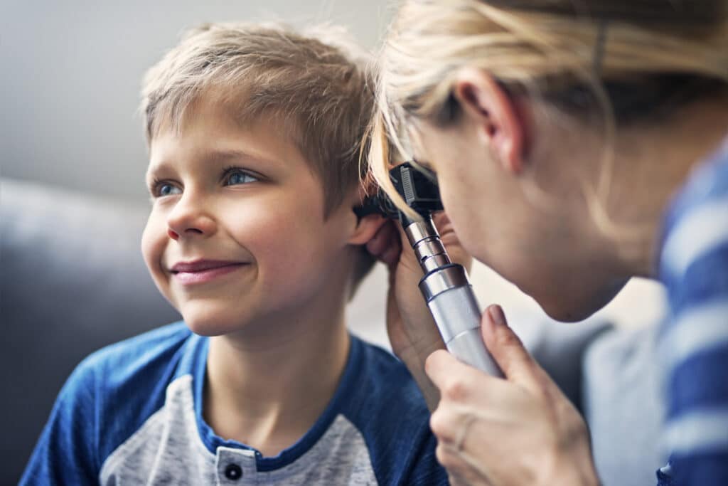 Petit garçon faisant examiner ses oreilles par un médecin.