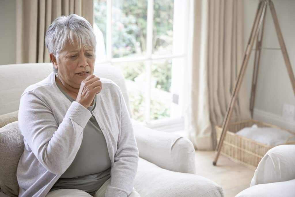 Femme avec une toux chronique se reposant dans sa maison.