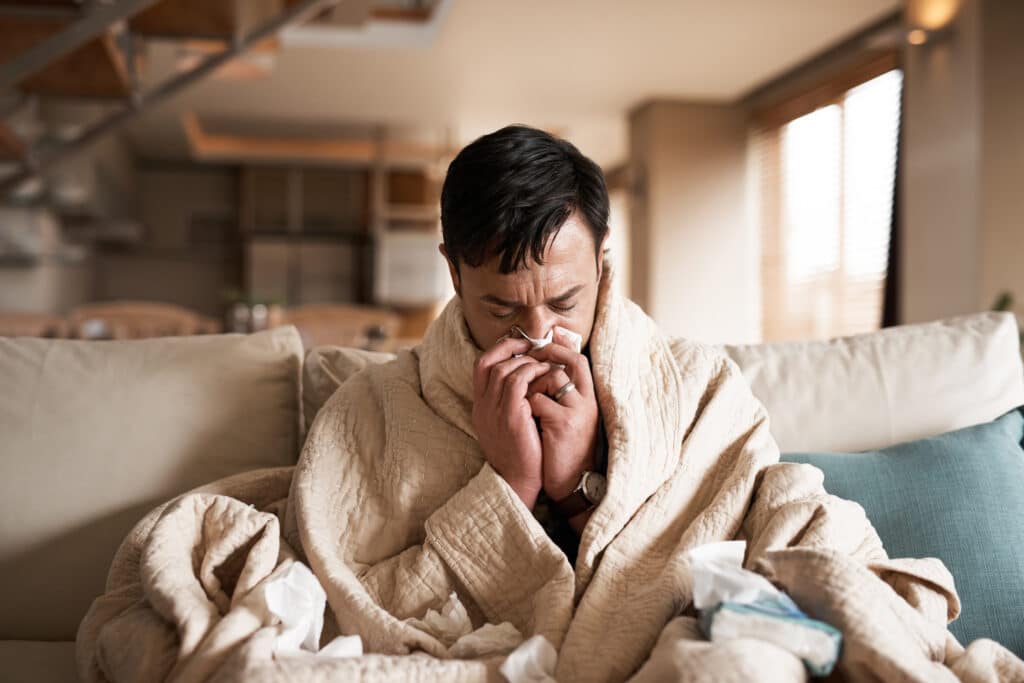 Un homme malade qui se mouche en se reposant à la maison.