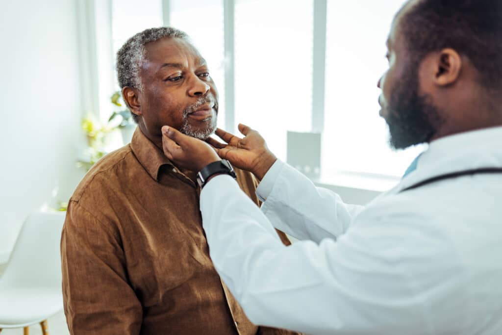 Médecin ORL effectuant un examen de la gorge sur un homme plus âgé,